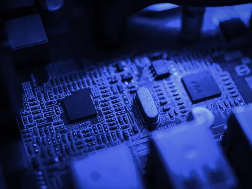 A closeup of the inside of a computer, with a focus on the circuit board, in blue light.
